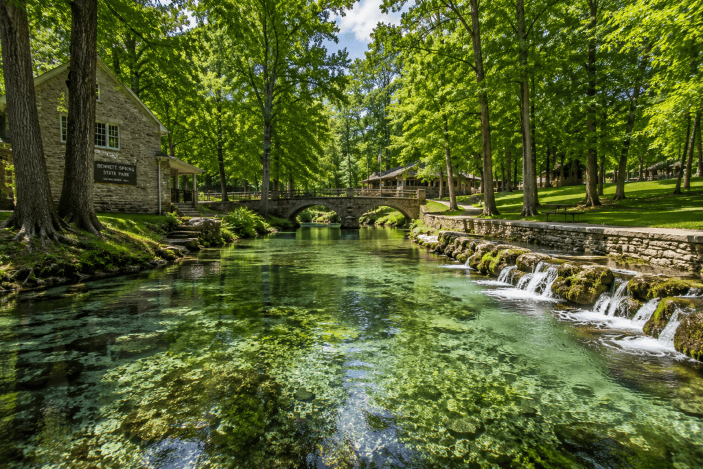 Clear spring water flowing through Bennett Spring State Park near Lebanon, Missouri, with stone bridges and wooded banks.